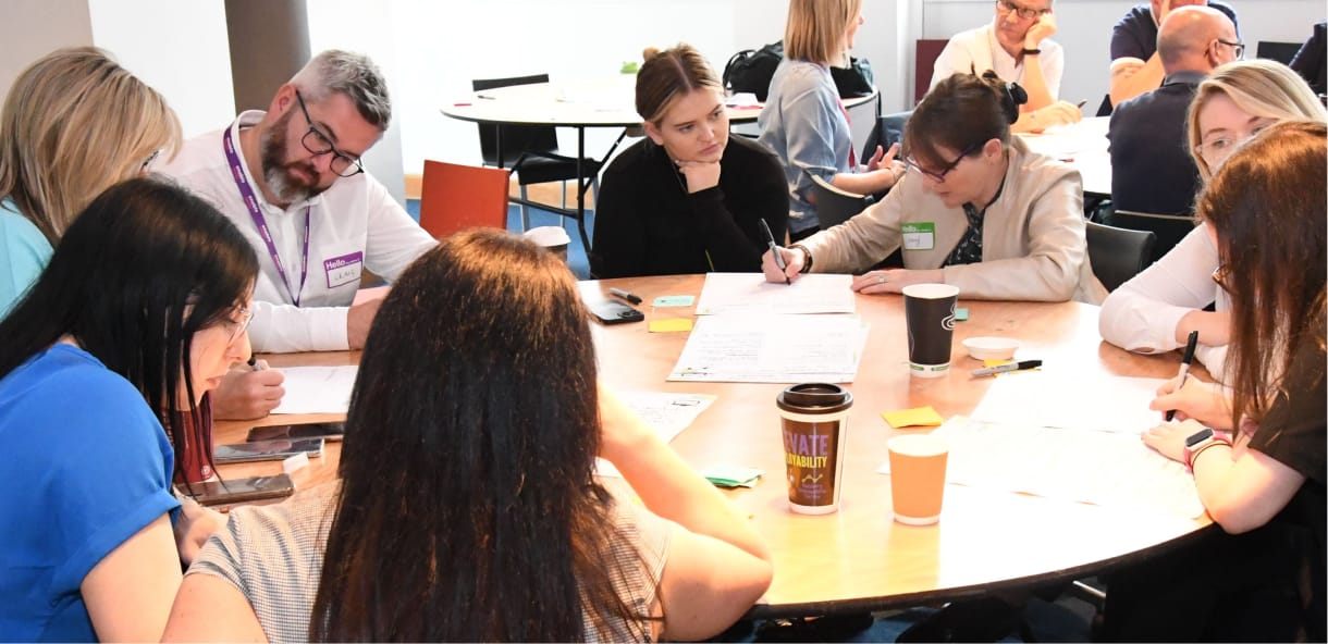 3 people taking part in a workshop in front of a whiteboard with education and transport written on it